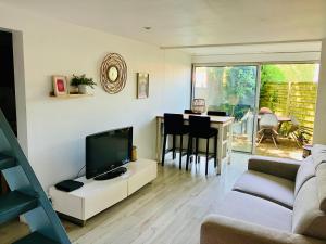 a living room with a couch and a tv and a table at Location Bassin Arcachon in Le Teich