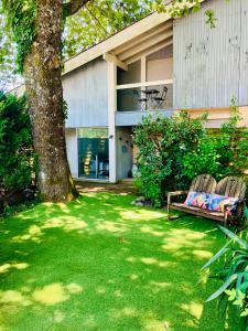 a house with a tree and two benches in a yard at Location Bassin Arcachon in Le Teich