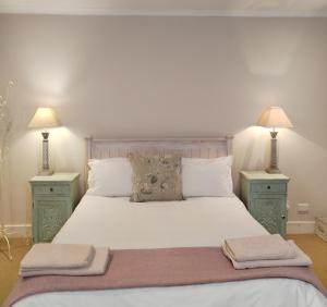 a bedroom with a white bed with two night stands at The Glades Cottage in Balgowan