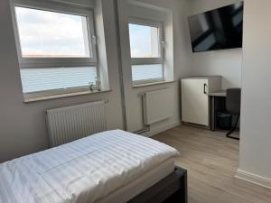 a bedroom with two windows and a bed and a desk at City Inn Schwedt in Schwedt