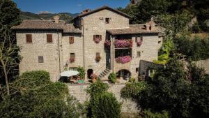 a large stone building with an umbrella in front of it at Arcera AGRITURISMO in Piana di Forcella