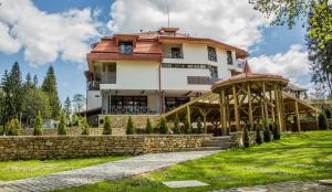 a large white building with a stone wall at Pensiunea Favorit Ferice in Borsec