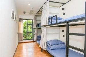 ein Zimmer mit drei Etagenbetten und einem Fenster in der Unterkunft Dengba International Youth Hostel - Shenzhen Futian Convention and Exhibition Center Branch in Shenzhen