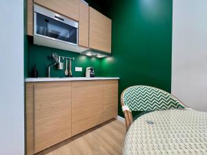 cocina con paredes verdes, fregadero y silla en La Suite Balinaise, en Quimper