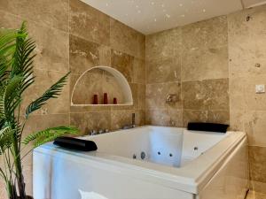 Una bañera en un baño con una pared de azulejos. en La Suite Balinaise, en Quimper 12 fotos más