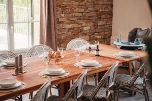 a wooden table with chairs and plates and wine glasses at Domaine du PIAOU "chambres & table d'hôte" in Le Val