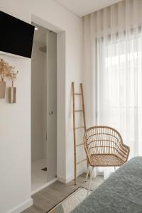 a bedroom with a chair and a ladder and a mirror at Consolação Surf & Pool Terrace in Atouguia da Baleia +26 photos