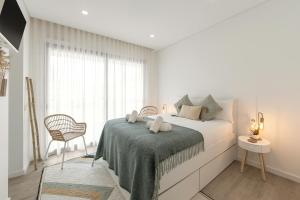 a white bedroom with a bed and a window at Consolação Surf & Pool Terrace in Atouguia da Baleia