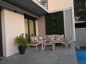 a couch on a patio with a green hedge at Villa luxueuse et Moderne avec piscine ! in Béziers