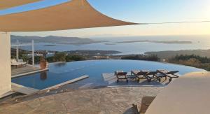 a swimming pool with chairs and a view of the water at Villa Pastorale-View-Boule Bahn in Agia Irini Paros