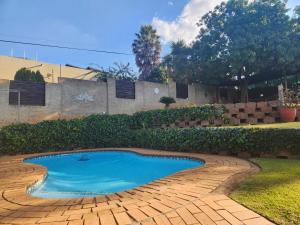 a small swimming pool in a yard with a brick pathway at Serenity Guest House in Roodepoort