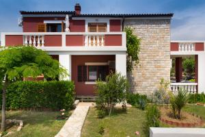 a red house with a garden in front of it at Sea Margarita Apartment in Pag