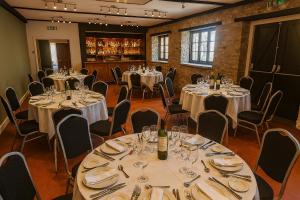 a room full of tables and chairs with wine glasses at The Swan Hotel Oxford in Eynsham