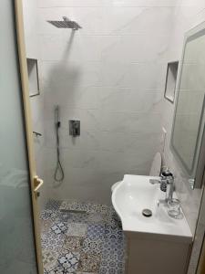 a white bathroom with a sink and a shower at Korca Center Apartment in Korçë