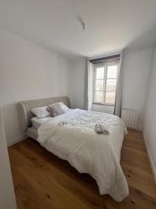 Una habitación blanca con una cama y una ventana en L'ideal, en Vannes