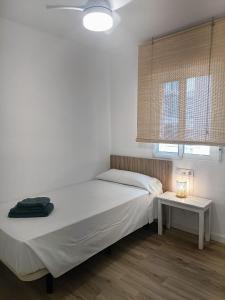 ein weißes Schlafzimmer mit einem Bett und einem Tisch in der Unterkunft Wind Rose Gandia Beach in Playa de Gandia