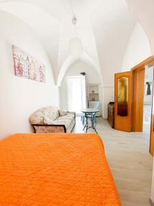 a bedroom with an orange bed and a couch at Casa Patty nel Vicolo in Ostuni