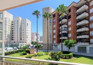einen Balkon mit Palmen und Gebäuden in der Unterkunft Wind Rose Gandia Beach in Playa de Gandia