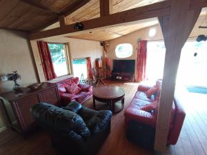 a living room with leather furniture and a table at Maison de caractère entre mer et campagne in Pluvigner