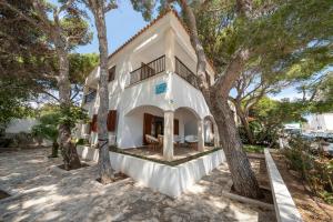 a white house with trees in front of it at Apartamentos MHM in Cala Ratjada