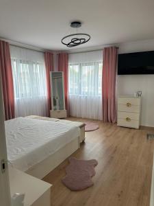a bedroom with a bed and a dresser and windows at Casa crisan in Mintiu Gherlii