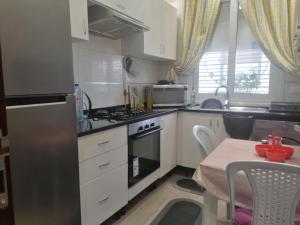 a kitchen with white cabinets and a stove and a table at Joli Appartement de LUXE in Sousse