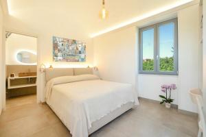 a white bedroom with a bed and a window at Oikos - Charm & Relax Procida in Procida