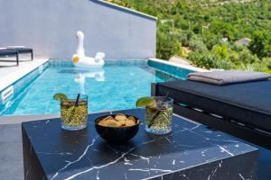 a table with a bowl of food and a swan in a pool at Villa Blue Sunset - Stunning Sea View Luxury Villa with Private Heated Pool in Brsečine