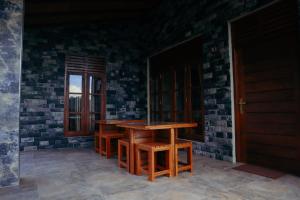 een houten tafel en banken voor een bakstenen muur bij The Hidden Heaven in Diyatalawa +28 foto's