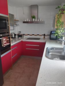 Una cocina con gabinetes rojos y un fregadero. en Villa Montoro, en Purchil