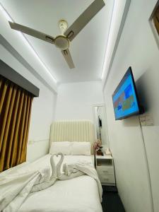 a bedroom with a bed with a ceiling fan and a tv at Maya by Xpressmall Hotels & Resorts in Kāmarpāra
