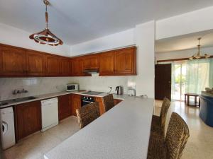 a kitchen with wooden cabinets and a table and chairs at Villa Koralia in Peyia