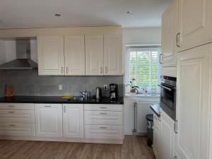 a kitchen with white cabinets and black counter tops at Lena in Dreumel