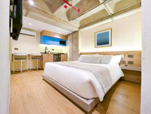ein Schlafzimmer mit einem großen weißen Bett und eine Küche in der Unterkunft Hotel Once22 in Sabaneta