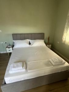 a large white bed with white sheets and pillows at The Sage House, Apt in Pogradec