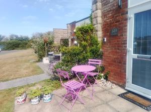 Una mesa y sillas moradas en un patio. en Fort Albert, en Freshwater 1 foto más