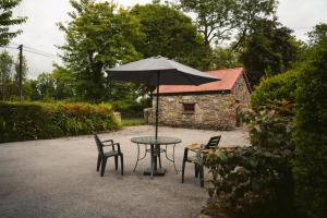 einen Tisch und Stühle mit Sonnenschirm im Hof in der Unterkunft Longford Holiday Kitty Kiernan's Self Catering Thatch Cottage in Longford