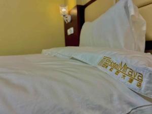 un letto con lenzuola bianche e cuscini sopra di Hotel Mirava a Maputo