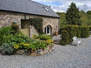 a stone house with a bench in front of it at Arrigle Cottage in Kilkenny