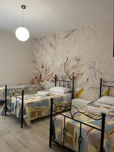 a room with three beds in front of a stone wall at Al Solito Posto Affittacamere in Alianello +7 photos