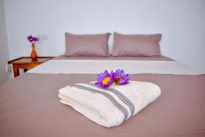 a white towel with purple flowers on top of a bed at Arcadiaa Villa in Polonnaruwa