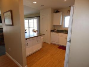 a kitchen with white cabinets and a wooden floor at Sunny Days at Shanty Creek in Bellaire