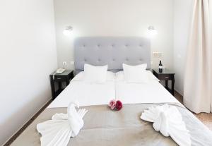 a bedroom with a bed with white sheets and two white gloves at Hotel Toboso Chaparil in Nerja