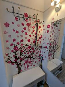 Un baño con un árbol con flores rosas en la pared. en Apartamentul Anei, en Constanţa
