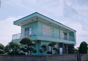 a blue house with a balcony on top of it at 寝室から太平洋を望む貸切別荘in海友荘 無料炭火BBQスペースと駐車場付 in Shirahama