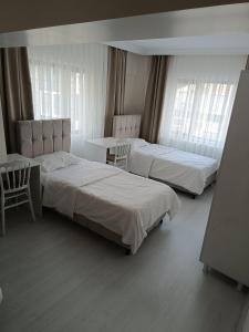 Un dormitorio con dos camas y una mesa y ventanas. en DENİZ BAYAN PANSİYON APARt, en Sivas