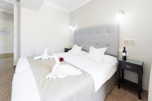 a bedroom with a white bed with a swan on it at Hotel Toboso Chaparil in Nerja