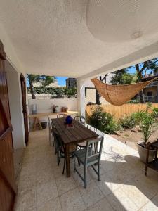een patio met een tafel en stoelen en een hangmat bij Grande maison familiale Leucate Village in Leucate