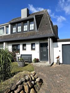 ein weißes Haus mit einer Bank davor in der Unterkunft Ferienhaus Berg in Sylt