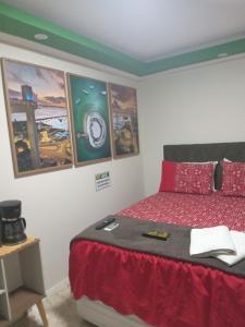 a bedroom with a bed and some paintings on the wall at Paraíso dos Viajantes - O PREFERIDO in Salvador